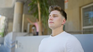 Genç, yakışıklı, beyaz, sakin ama ciddi bir yüz ifadesi sergiliyor, açık havada güneşli bir havada dikilirken yan tarafa bakıyor. Sokak modası şehir ve havalı yaşam tarzını gözler önüne seriyor.