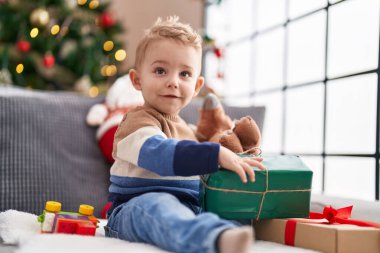 Evdeki kanepede oturan sevimli bebek Noel hediyesini açıyor.