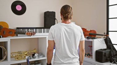 Genç İspanyol müzisyen müzik stüdyosunda geriye doğru duruyor.