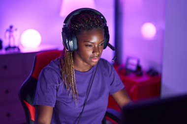 Oyun odasında bilgisayar kullanarak video oyunu oynayan Afro-Amerikan kadın flaması.
