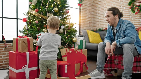 Father and son putting gift on christmas tree at home
