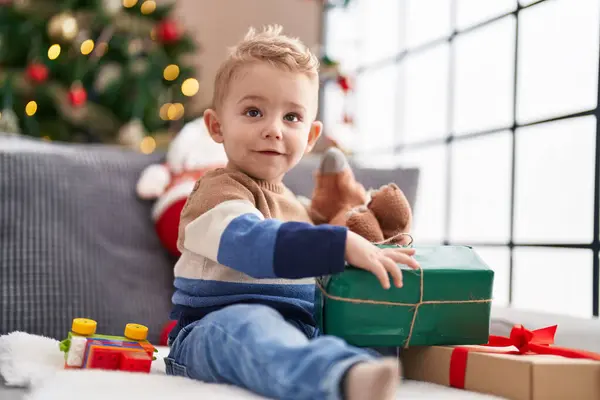 愛らしい幼児Unpackingクリスマスギフト座っています上のソファにホーム — ストック写真