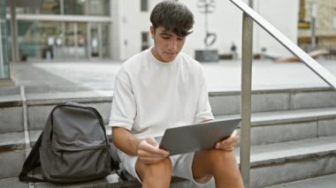 O anda yakalanmış, gülümseyen, yakışıklı, İspanyol asıllı genç üniversite merdivenlerine çıkıyor, öğrenci hayatı hokkabazlık yapıyor, günışığı günlük yaşam tarzını değiştiriyor ve güzel bir video aracılığıyla online eğitim alıyor.