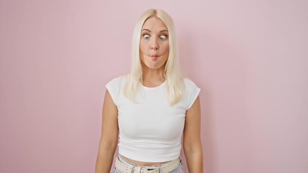 Mladá Blondýnka Komicky Stojící Nad Izolovaným Růžovým Pozadím Dělá Bláznivé — Stock video