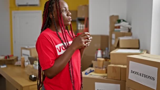 严肃的非洲裔美国妇女志愿者 穿着制服站在社区慈善中心的室内品尝咖啡 体现了利他主义的服务精神 — 图库视频影像