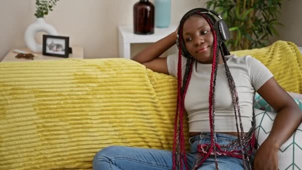 Radosna Afrykańska Kobieta Pięknie Pewna Siebie Siedząca Kanapie Salonie Muzyka — Wideo stockowe