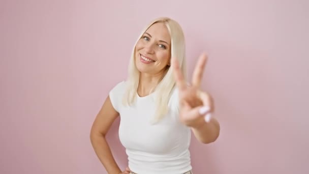 Bubbly Νεαρή Ξανθιά Γυναίκα Στέκεται Χαμογελώντας Αυτοπεποίθηση Δείχνει Δύο Δάχτυλο — Αρχείο Βίντεο