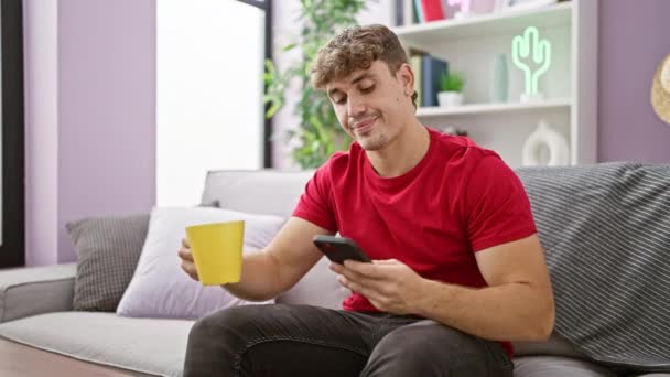 Yakışıklı Genç Spanyol Adam Evde Dinleniyor Kanepede Kahve Içerken Mesaj — Stok video
