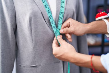Young arab man tailor measuring jacket at tailor shop
