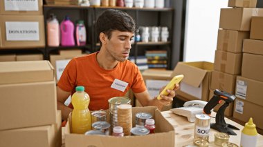 Kendini işine adamış genç İspanyol gönüllü gönüllü toplum merkezindeki akıllı telefonuyla yardım ürünlerini kontrol ediyor.