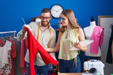 Man and woman tailors holding t shirt looking clothing design at clothing factory