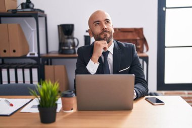Ofiste çalışan orta yaşlı kel bir adam ciddi bir yüz ifadesi, eli çenesinde soru soran, kafa karıştırıcı bir fikir hakkında düşünceli. 