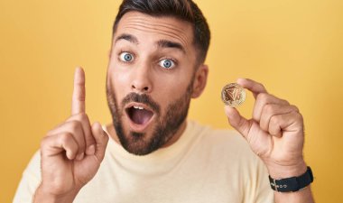 Tron kripto para tutan yakışıklı İspanyol adam bir fikir ya da soru işareti ile şaşırdı mutlu bir yüzle, bir numara 