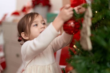 Noel ağacını süsleyen sevimli kız evde duruyor.