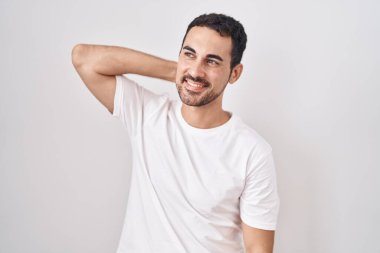 Beyaz arka planda duran yakışıklı İspanyol adam gülümsüyor. Kendine güvenen, el hareketleriyle saçlara dokunan, çekici ve modaya uygun poz veren. 