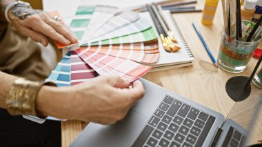 Bir sanat stüdyosunun kalbinde, yaşlı bir kadın sanatçının elleri bir boya rengi seçerken görülüyor, sevdiği hobisine dalmış.