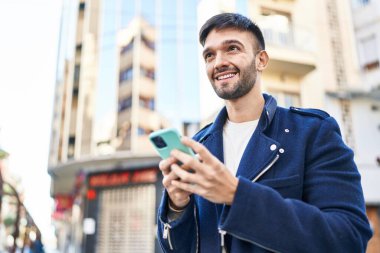 Sokakta akıllı telefon kullanan, kendine güvenen genç bir İspanyol.