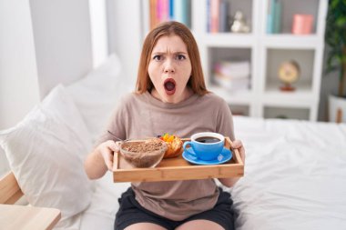 Elinde kahvaltı tepsisiyle pijama giyen kızıl saçlı kadın şaşkınlık ve şaşkınlık dolu bir ifade, korku ve heyecan dolu bir yüz ifadesiyle şok olmuştu.. 