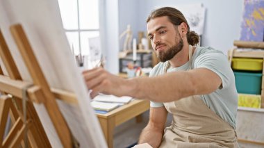 Sanat stüdyosunda resim çizen genç bir İspanyol.