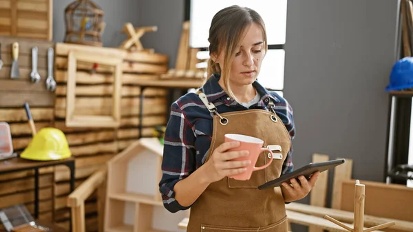 Attractive Young Blonde Carpenter Woman Coffee Hand Navigating Touchpad Amidst — Stock Photo, Image