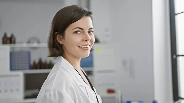 Radiant smile lighting up the lab, young, confident and beautiful hispanic woman scientist joyfully working, standing amidst the thrilling buzz of medical research and discovery.