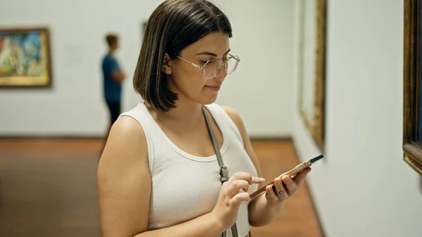 Young beautiful hispanic woman visiting art gallery using smartphone at Albertina Museum in Vienna