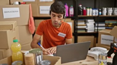 Genç, çekici İspanyol erkek gönüllü, hayır kurumunda evde otururken içten bir şekilde gülümsüyor. Laptop 'taki video görüşmesi sırasında istekle not alıyor. Toplum desteğiyle ilgileniyor.