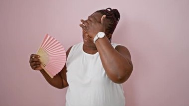 Afro-Amerikalı kadın izole edilmiş pembe arka plan için acı çeken el fanı kullanıyor.