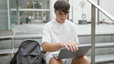 Zeki bir üniversite öğrencisi olan havalı İspanyol ergen, dizüstü bilgisayarını bitiriyor, şimdi de kampüs noktasında akıllı telefonuyla mesajlaşıyor.