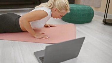 Çekici genç sarışın kadın cidden geriniyor. Evde yoga kursunda meditasyon yapıyor.