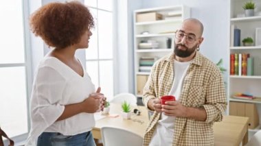 İki kendine güvenen işçi, bir erkek ve bir kadın, sabah kahvesinin tadını çıkarıyorlar ve iş yerlerinde rahatça konuşuyorlar, başarıyı ve profesyonel takım çalışmasını somutlaştırıyorlar.