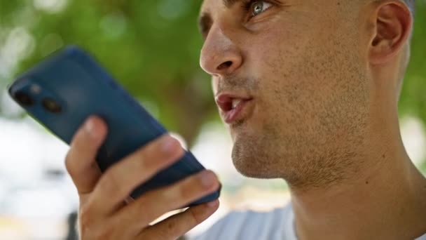 在一个自然公园里 一个英俊的年轻人在户外用智能手机 把注意力集中在设备上 — 图库视频影像