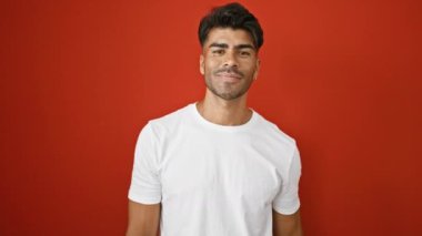 Beyaz gömlekli yakışıklı, kırmızı duvarın karşısında gülümseyen, başparmak kaldıran.