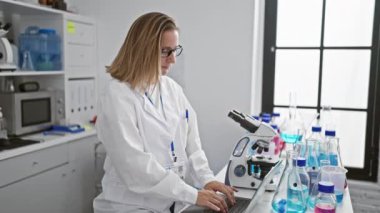 Canlı sarışın bilim adamı, laboratuvarda dizüstü bilgisayarı üzerinde çalışırken, modern araştırma dünyasındaki teknoloji ve biyolojinin güzel bir karışımını somutlaştırırken bir anlık neşe yakaladı.