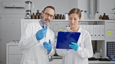 Laboratuvarda test tüpü tutan iki bilim adamı not alıyor.