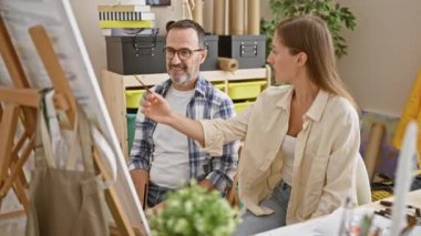 Sanat stüdyosunda iki sanatçının neşeli anı, erkek ve kadın yaratıcılıklarını kutlarken beşlik çakıyorlar.