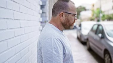 Suratı ciddi bir şekilde duvara yaslanmış beyaz bir adam.