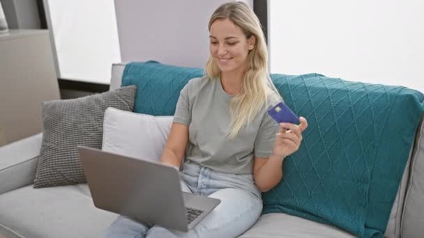 Blond Kvinna Som Håller Kreditkort Och Skrattar Medan Arbetar Laptop — Stockvideo