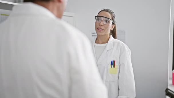 自信的男女科学家在一起 愉快地谈论他们在室内实验室的最新发现 沉浸在生物研究和显微镜下的化学分析中 — 图库视频影像