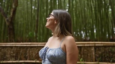 Gözlüklü güzel İspanyol kadın, Kyoto 'nun yemyeşil bambu ormanlarının arasında durup etrafa bakıyor, neşe ve şaşkınlık içinde..