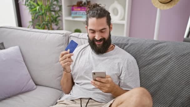 Ένας Χαρούμενος Γενειοφόρος Άνδρας Ελέγχει Smartphone Του Κρατώντας Μια Πιστωτική — Αρχείο Βίντεο