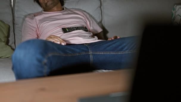 一个男人抱着遥控器睡在沙发上 睡在舒适的客厅里 — 图库视频影像