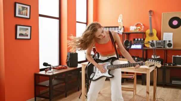 年轻的高加索女音乐家在一个充满活力的橙色音乐工作室里弹奏吉他 激发了创造力和才华 — 图库视频影像