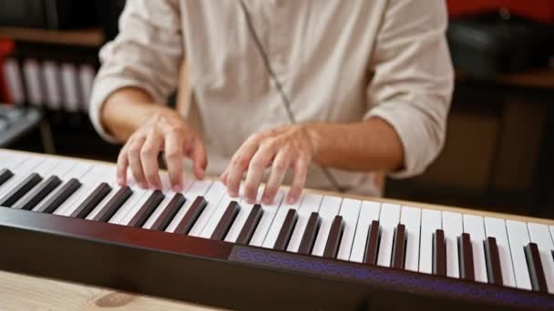 Молодой Латиноамериканец Играющий Клавишных Студии Наушниками Гитарой Заднем Плане — стоковое видео
