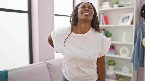 Afroamerikanerin Mit Lockigem Haar Die Einem Wohnzimmer Rückenschmerzen Ausdrückt Trägt — Stockvideo