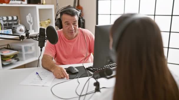 プロの男性と女性のインタビュー者は ラジオスタジオでヘッドフォンを削除し ライブ放送をラップしながら 光の瞬間を共有します — ストック動画
