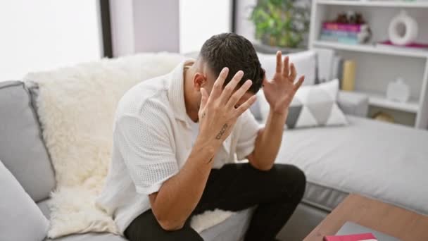 自宅で絶望的な若いアラブの男性 ストレスをナビゲート 片頭痛 苦しみと痛みは ソファに座っている間 手のひらひらめき頭 — ストック動画