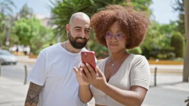 Güzel bir çift, gülüyorlar ve kenar mahallede birbirlerine güveniyorlar, gülümsüyorlar ve akıllı telefonlarından mesajlarını paylaşıyorlar.