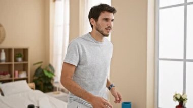 Günlük giysiler içinde yakışıklı genç bir İspanyol, evde koşarken odaklanmış görünüyor, sağlık ve zindelik taşıyor..