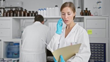 Bilimin kalbinde, iki sadık laboratuvar arkadaşı, erkek ve kadın bilim adamı, akıllı telefonla konuşuyorlar, laboratuvar analizleri ve araştırmalar sırasında birlikte belge okuyorlar.